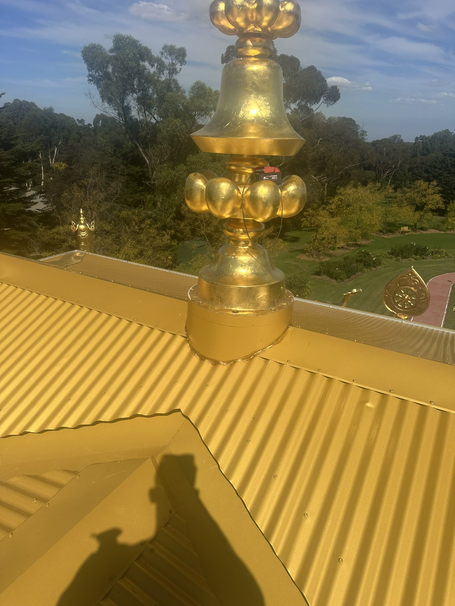 Hand-formed flashing around a gold monument on the temple roof